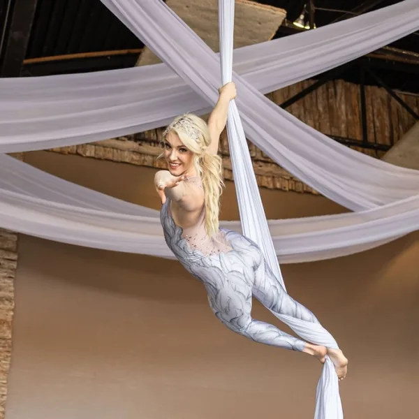 Aerial silk performer in white costume entertaining guests at Nashville wedding reception with draped fabric ceiling decor
