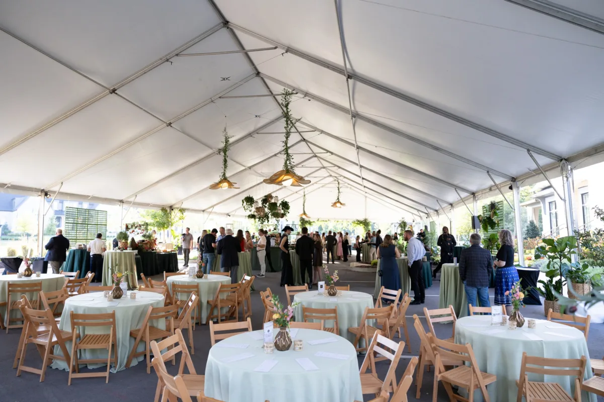Corporate social event reception under white tent with round tables and wooden chairs catered by A Catered Affair in Nashville