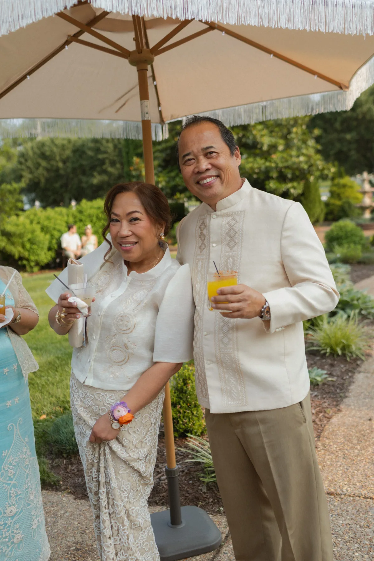 Couple in traditional Filipino barong tagalog and formal white attire enjoying cocktails at outdoor wedding reception in Nashville