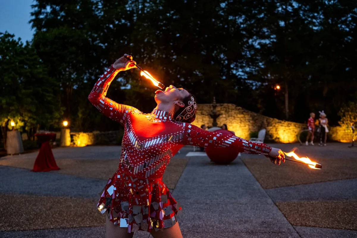 Professional fire performer in sequined costume entertaining guests at evening Nashville wedding event catered by A Catered Affair