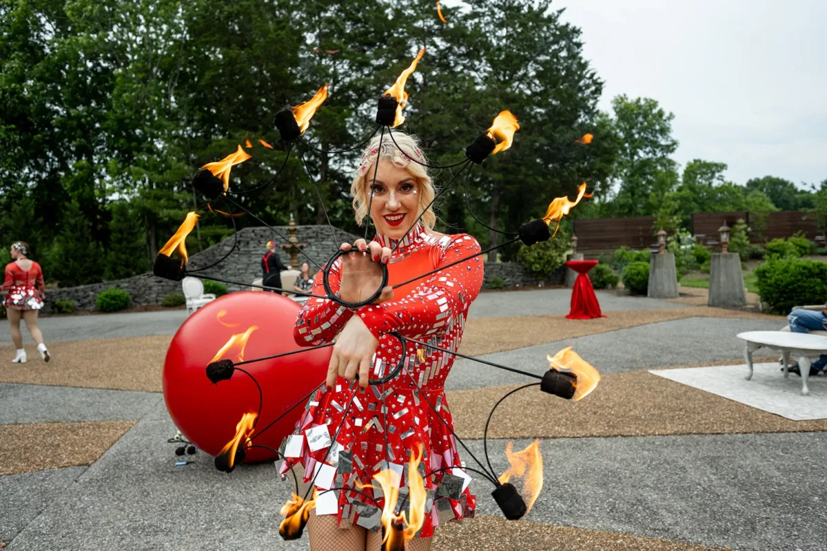 Professional fire performer in red dress entertaining guests at Nashville wedding event catered by A Catered Affair