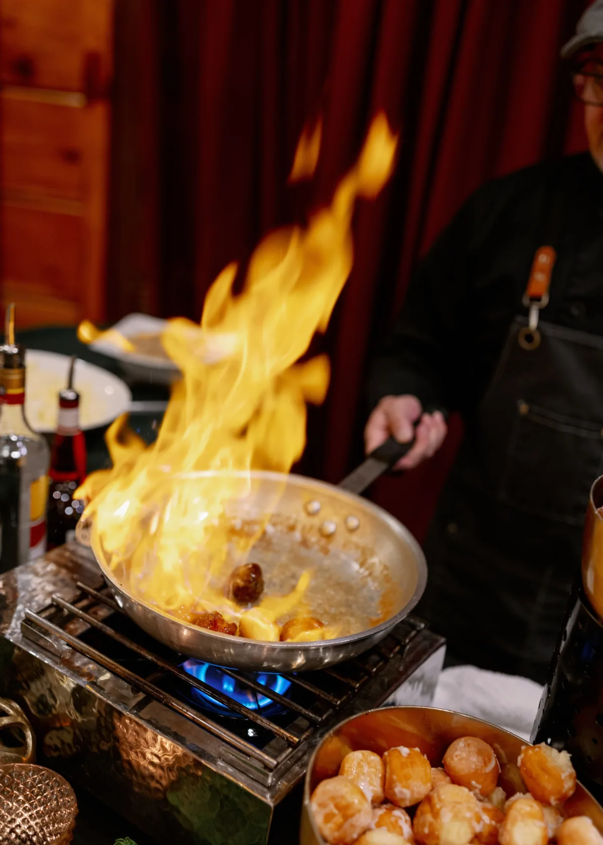 Dramatic flaming tableside cooking presentation by Nashville wedding caterer A Catered Affair with chef preparing flambéed dish