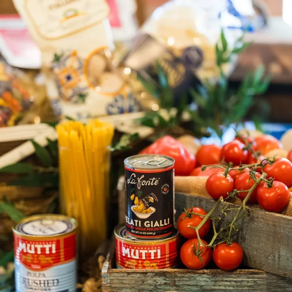 Italian wedding catering display featuring fresh vine tomatoes, pasta, and gourmet canned goods by A Catered Affair Nashville wedding caterer