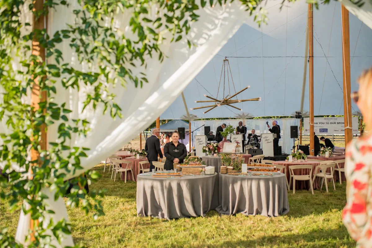Elegant outdoor wedding reception under white tent with round tables and catering setup by A Catered Affair in Nashville