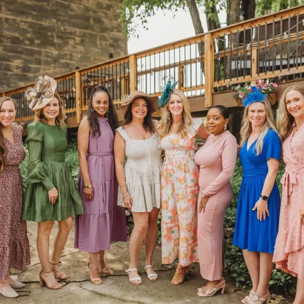 Elegant bridal party in colorful dresses and fascinators celebrating at outdoor Nashville wedding venue catered by A Catered Affair