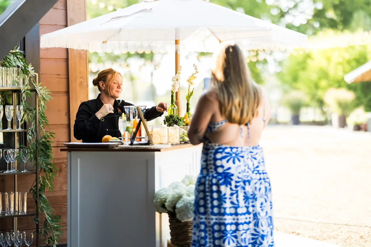 Professional bartender serving drinks at outdoor Nashville wedding reception with elegant bar setup by A Catered Affair