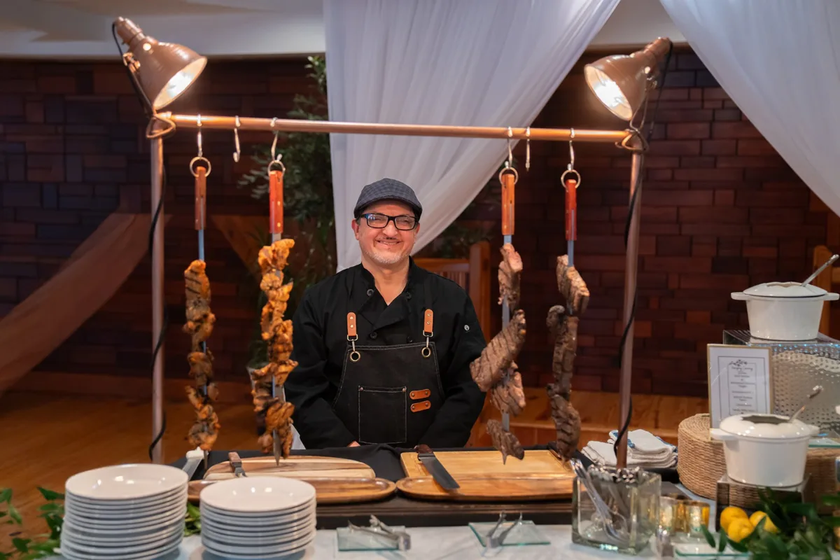 Professional chef from A Catered Affair preparing grilled meats at elegant Nashville wedding reception with copper heat lamps and white linens