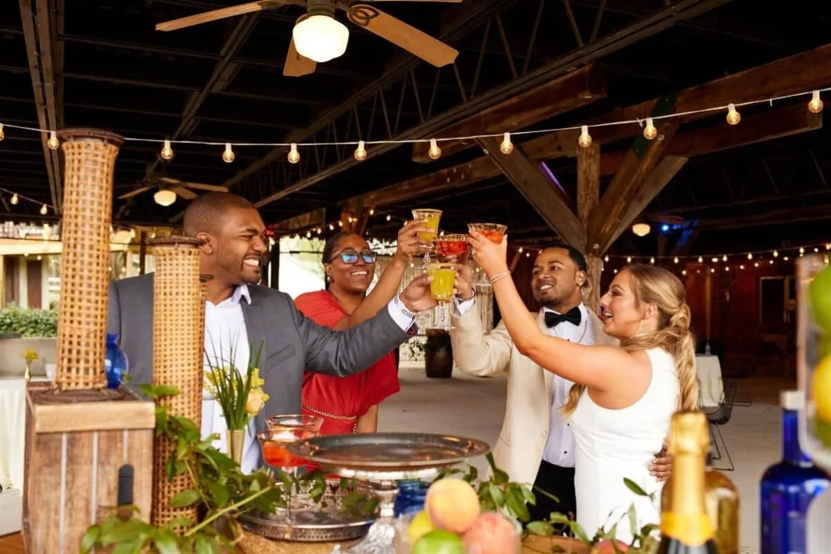 Wedding guests raising cocktails in celebratory toast during cocktail hour catered by A Catered Affair in Nashville