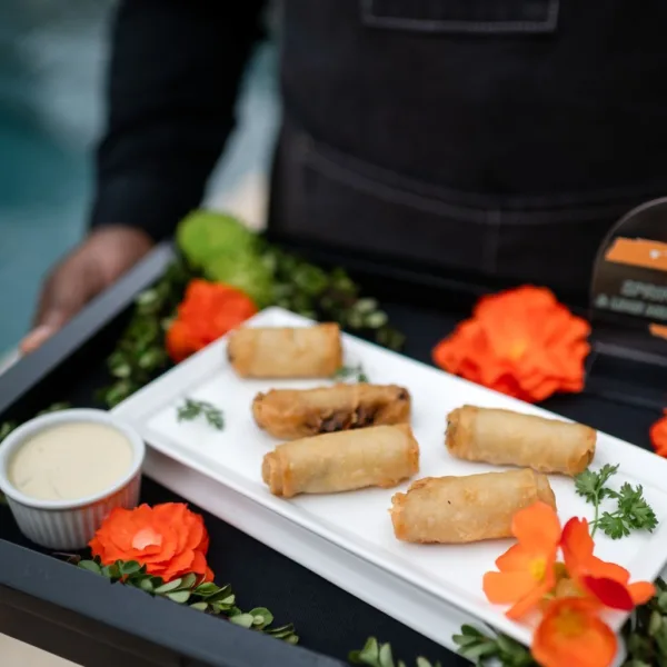 Elegant spring roll appetizers with dipping sauce and floral garnish by Nashville wedding caterer A Catered Affair