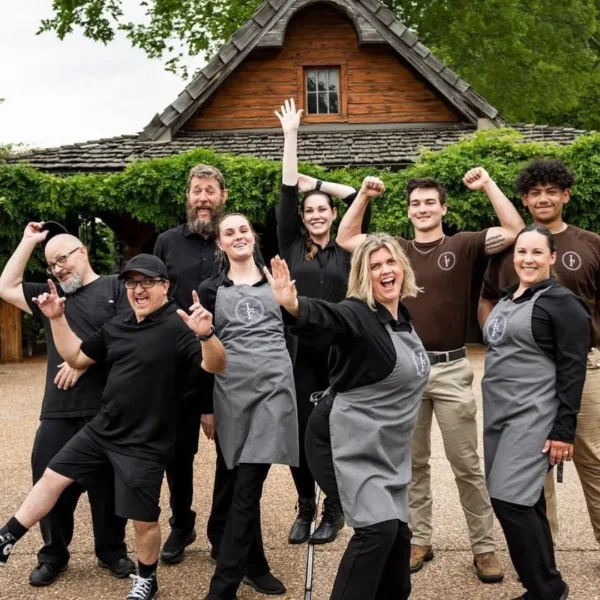A Catered Affair Nashville wedding catering team celebrating together in matching aprons at rustic venue
