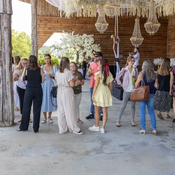 Wedding guests enjoying cocktail hour at rustic Nashville venue with wooden beams and hanging chandeliers catered by A Catered Affair