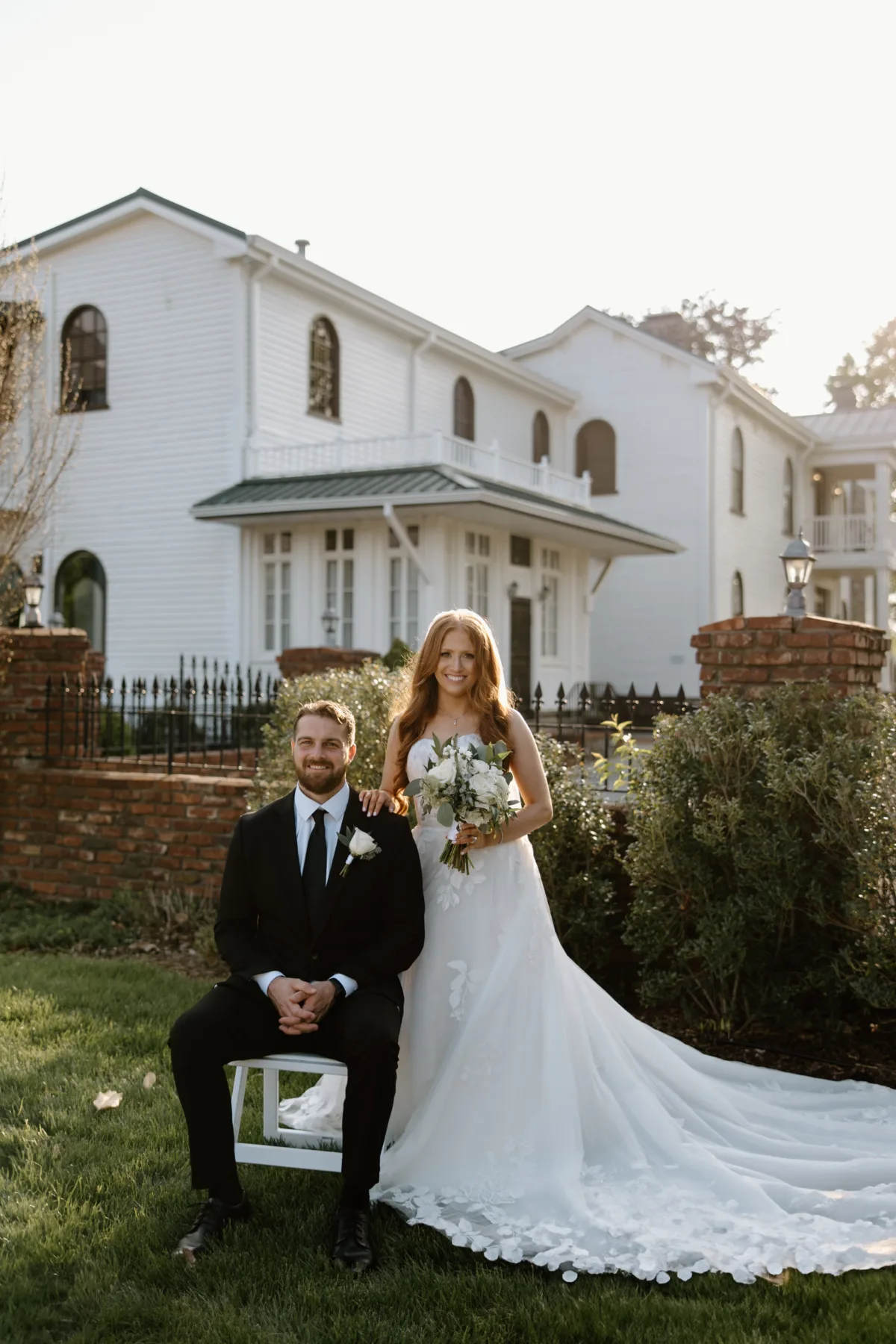 Elegant wedding couple portrait on manicured venue grounds in Nashville with bride in flowing gown and groom in black tuxedo for A Catered Affair wedding catering