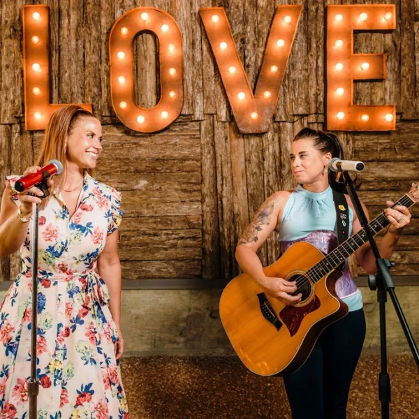 Acoustic duo performs at Nashville wedding reception with illuminated LOVE marquee letters backdrop
