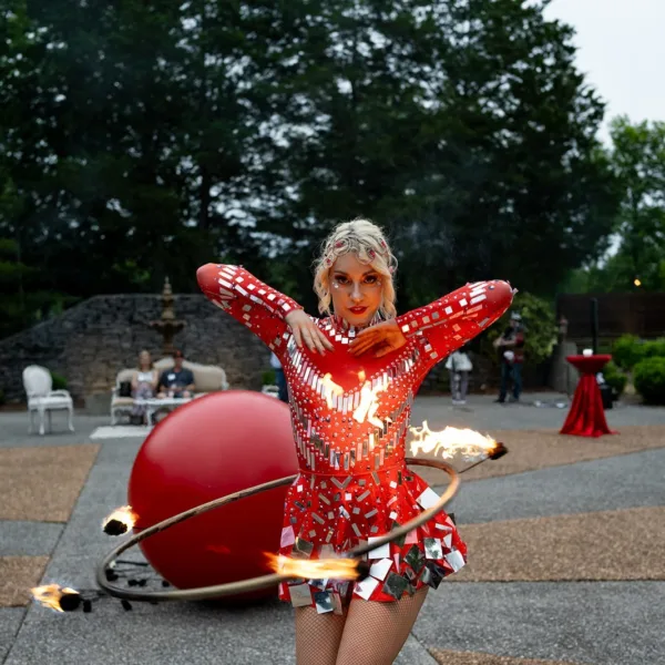 Professional fire performer in red sequined costume entertaining guests at Nashville wedding event with flaming hoop act