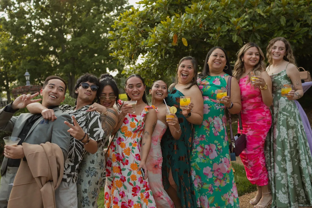Wedding guests in colorful floral dresses celebrating with cocktails at outdoor Nashville wedding reception catered by A Catered Affair