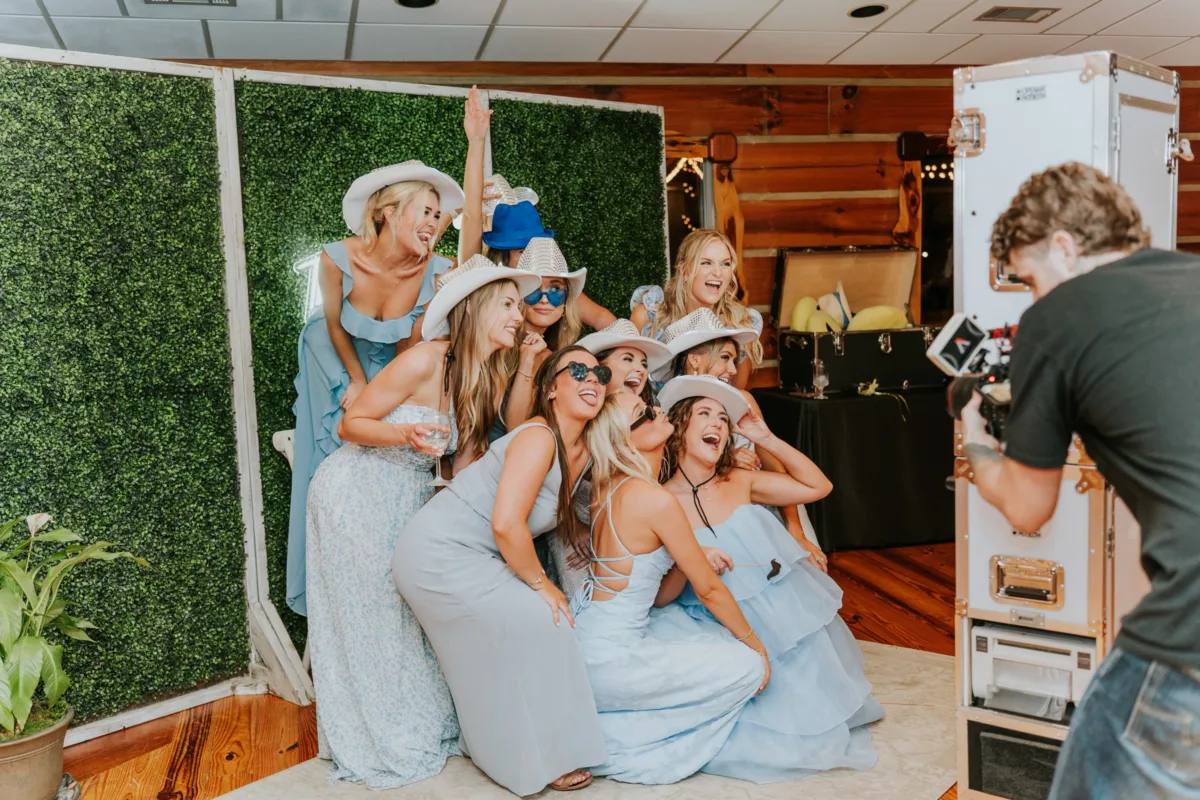 Bridesmaids in blue dresses and white cowboy hats posing at wedding photo booth in Nashville