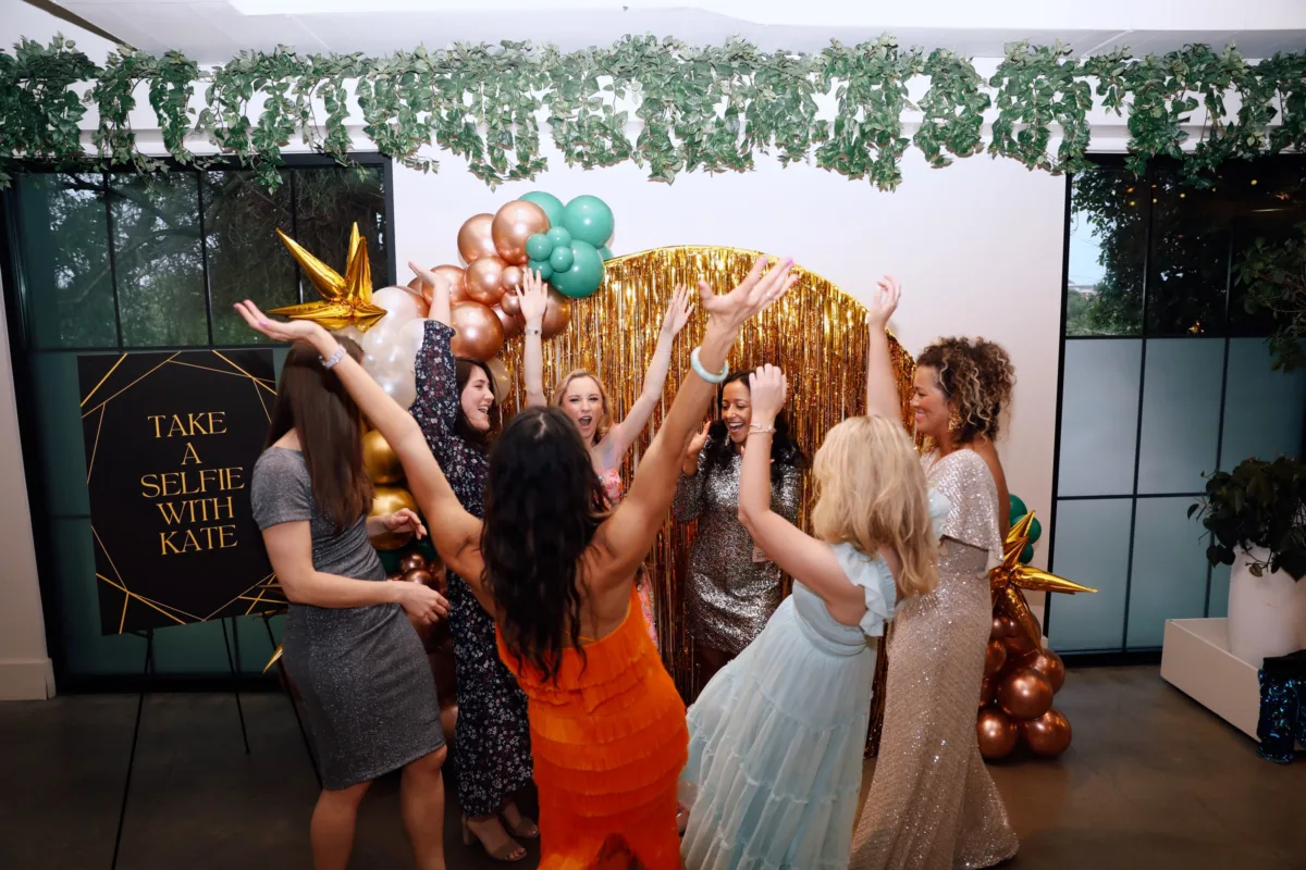 Wedding guests celebrating at photo booth with gold backdrop and balloons at Nashville wedding catered by A Catered Affair