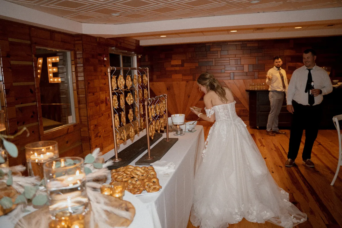 Bride at pretzel station during Nashville wedding reception catered by A Catered Affair with warm lighting and brick walls