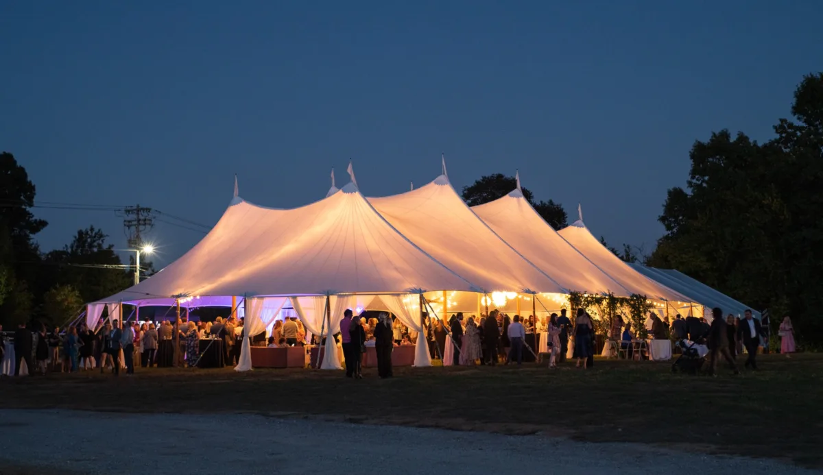 Elegant outdoor wedding reception under illuminated white tent catered by A Catered Affair in Nashville with guests dining at twilight