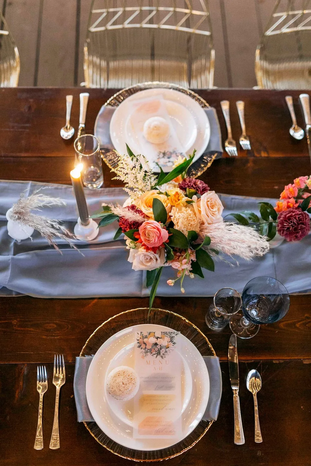 Elegant wedding tablescape with autumn floral centerpiece featuring roses and pampas grass, gold rimmed plates and glassware on wooden farm table in Nashville
