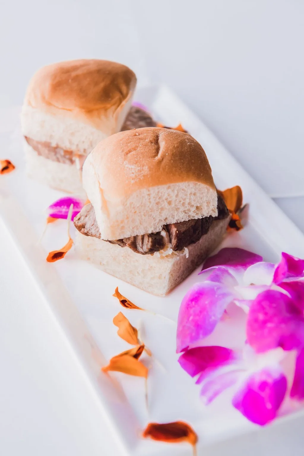 Elegant slider appetizers with chocolate filling served on white plate with purple orchid petals by Nashville wedding caterer A Catered Affair