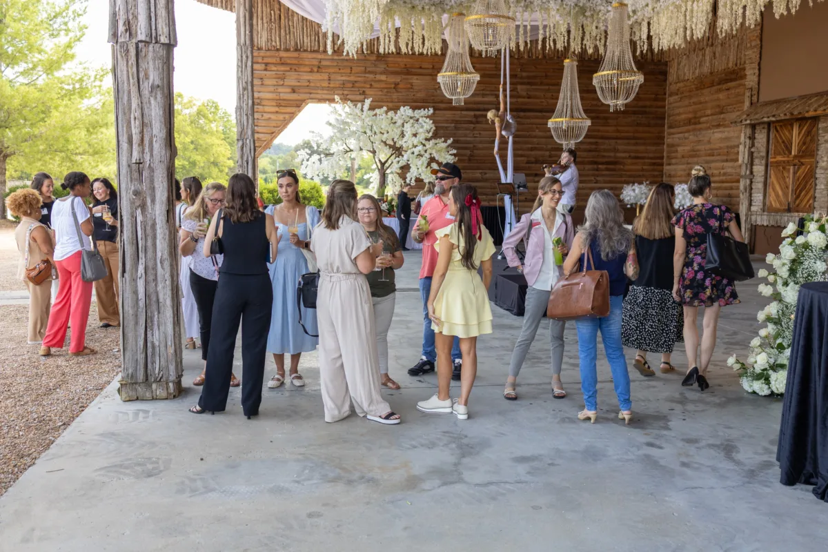 Wedding guests enjoying cocktail hour at rustic Nashville venue with wooden beams and wicker chandeliers catered by A Catered Affair