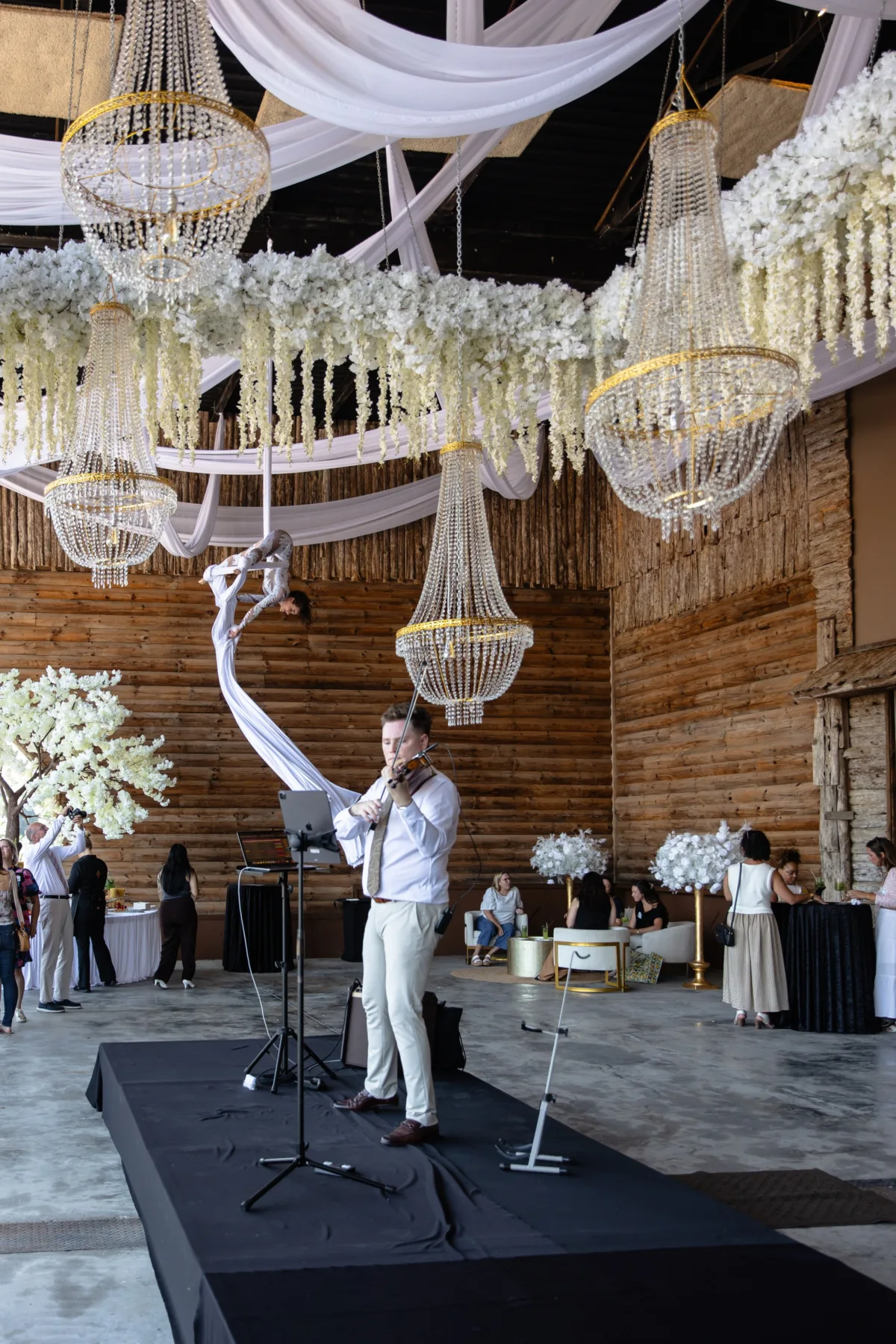 wedding violinist performance elegant chandelier reception venue - Nashville Private Event Catering Violinist performs at elegant wedding reception with crystal chandeliers and white floral arrangements at Nashville venue